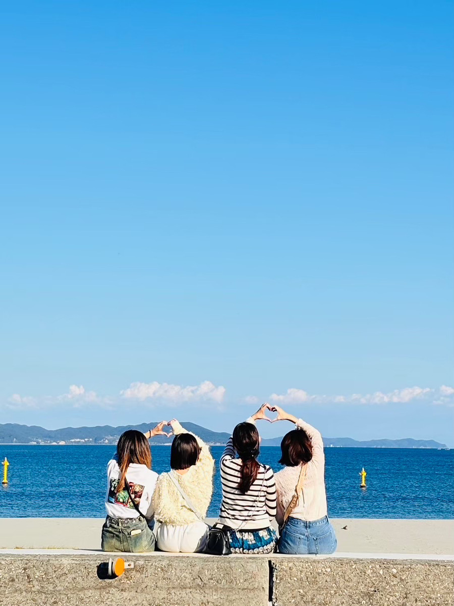 海を眺めながら仲間とハートを作る様子