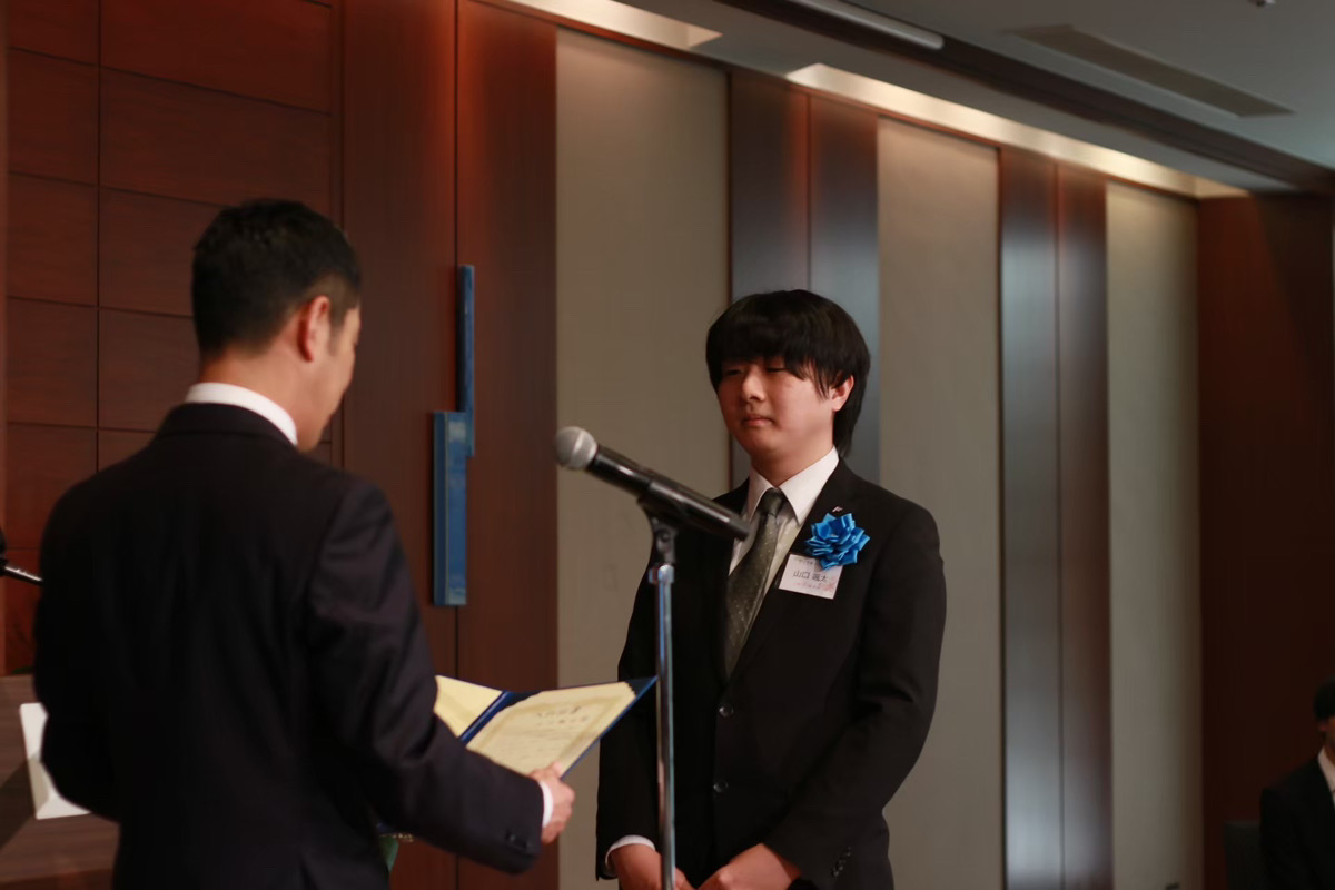 入社式で新入社員が辞令を受け取る様子